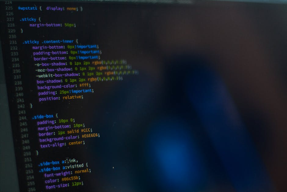 A computer screen displaying a close-up of a web browser window filled with lines of code in various colors including red, green, blue, and purple on a dark background. The code appears to be HTML or 